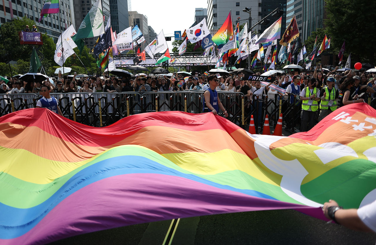 A large rainbow flag is held in front of participants of 2026 Seoul Queer Parade in central Seoul on Saturday. (Yonhap)