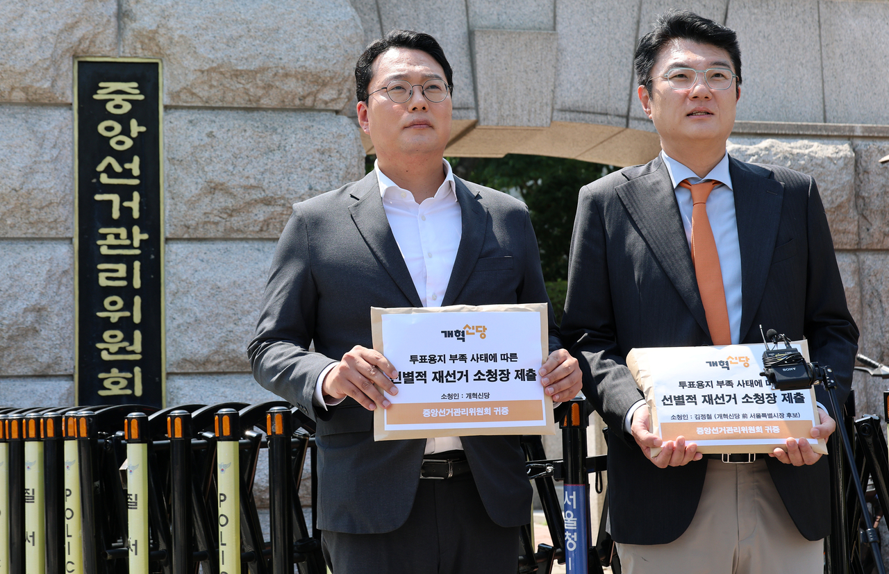Rep. Chun Ha-ram (left) and Kim Jung-chul of the Reform Party pose for photos in front of the National Election Commission headquarters in Gwacheon, Gyeonggi Province, on Monday. (Yonhap)
