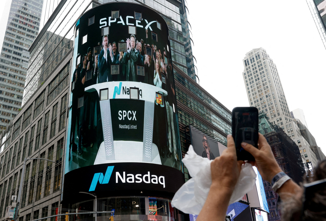 People gather to watch a live feed with SpaceX CEO Elon Musk on the day of SpaceX's initial public offering at the Nasdaq MarketSite in New York City on Friday.   Reuters-Yonhap
