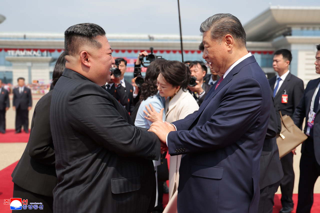 This photo shows the North's leader Kim Jong-un (L) shaking hands with Chinese President Xi Jinping at Pyongyang Sunan International Airport on June 9. (KCNA-Yonhap)