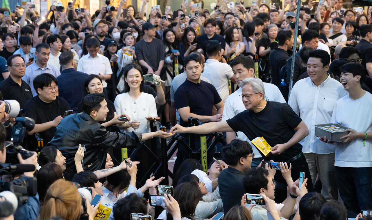 Nvidia CEO Jensen Huang hands out chips to a packed crowd outside a samgyeopsal restaurant near Hongdae on Friday evening. (Yoon Chang-bin/The Korea Herald)