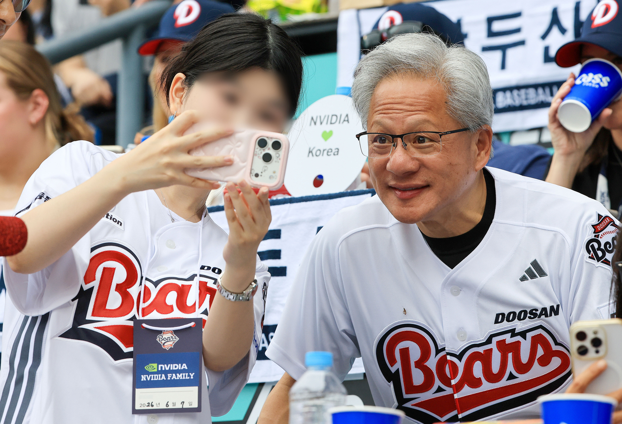 Nvidia CEO Jensen Huang poses with fans in a Doosan Bears jersey at Jamsil Baseball Stadium in Seoul on Sunday, after throwing the ceremonial first pitch at a KBO game. (Joint Press Corps-Yonhap)