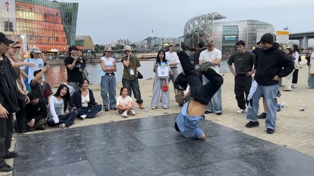 A b-boy performs during a battle at the Hangang Jam on June 6. The three people seated in the center are members of the general public who volunteered to serve as judges, blurring the line between participants and spectators. (Tammy Park/The Korea Herald)