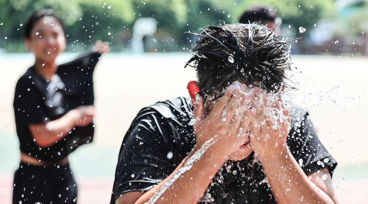 Students at the Gyeongsan Middle School in Gyeongsan, North Gyeongsang Province, wash their faces after gym class on Wednesday. The nation's first heat wave warning was issued Wednesday in Gyeongsan and other parts of the province. (Yonhap)