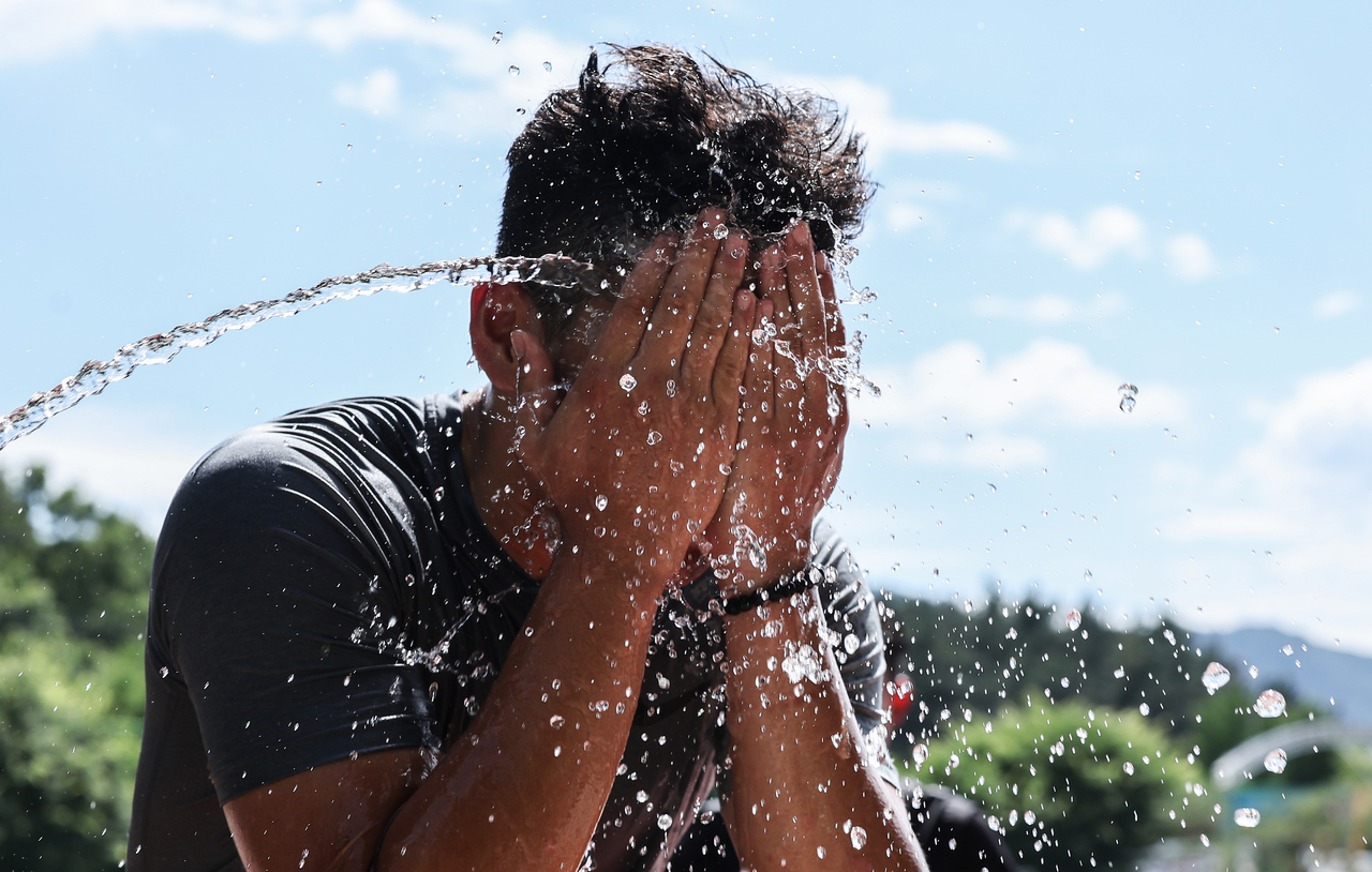 A man washes his face at a middle school in the southeastern city of Gyeongsan on June 17, 2026, a day before a heat wave advisory was issued for the city. (Yonhap)