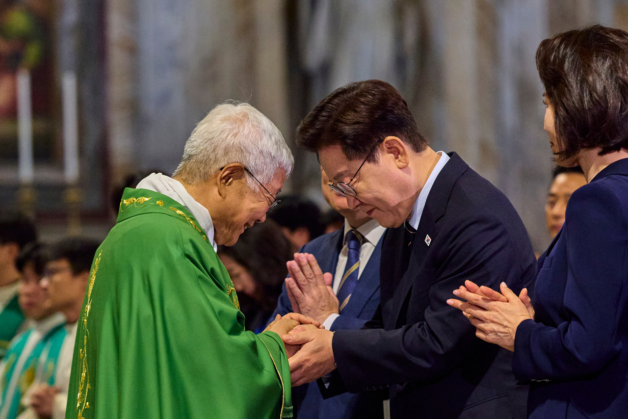 President Lee Jae Myung (right) shakes hands with Cardinal Lazzaro You Heung-sik after the cardinal delivered a homily during a special Mass at the Basilica of Saint Paul Outside the Walls in Rome on Sunday. (Joint Press Corps via Yonhap)