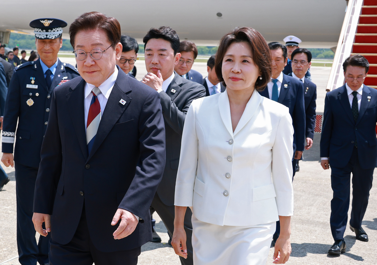 President Lee Jae Myung (front left) and first lady Kim Hea Kyung (on Lee's left) leave Air Force One at Seoul Air Base in Seongnam on Thursday, after returning from Lee’s European tour and the G7 summit. (Yonhap)