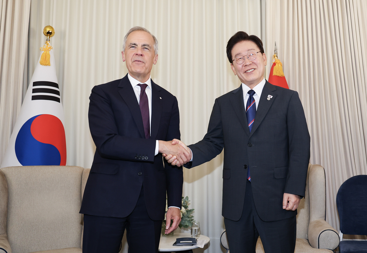 President Lee Jae Myung and Canadian Prime Minister Mark Carney shake hands ahead of talks held on the sidelines of the G7 summit in Evian-les-Bains, France, on Tuesday. (Yonhap)