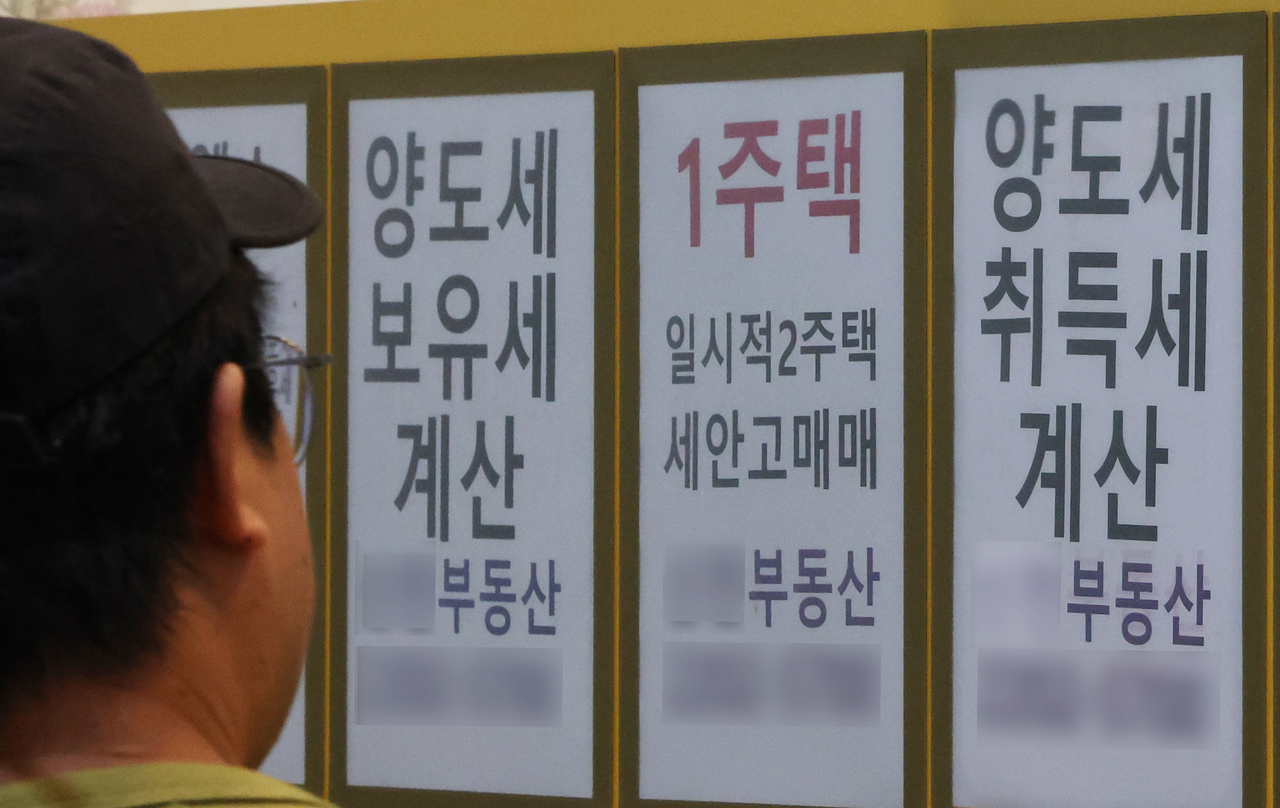 A passerby views a bulletin board for a real estate brokerage in Songpa-gu, Seoul, Sunday. (Yonhap)