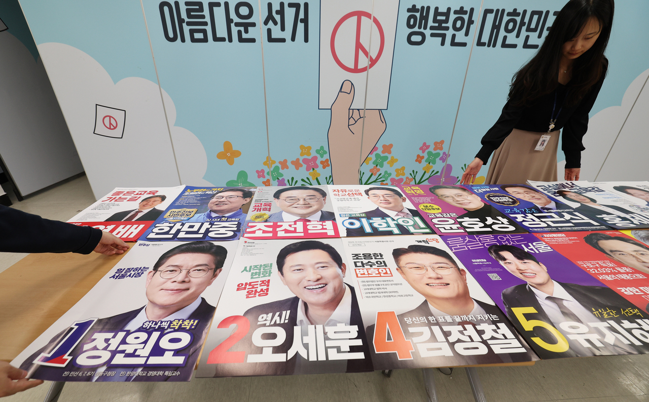 An election official checks posters of candidates running in the June 3 local elections at an election management committee office in Seoul . (Yonhap)