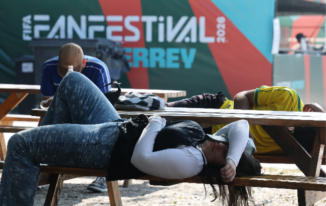 People lie on shaded benches to avoid the heat at the FIFA Fan Festival in Monterrey, Mexio, Monday. (Yonhap)