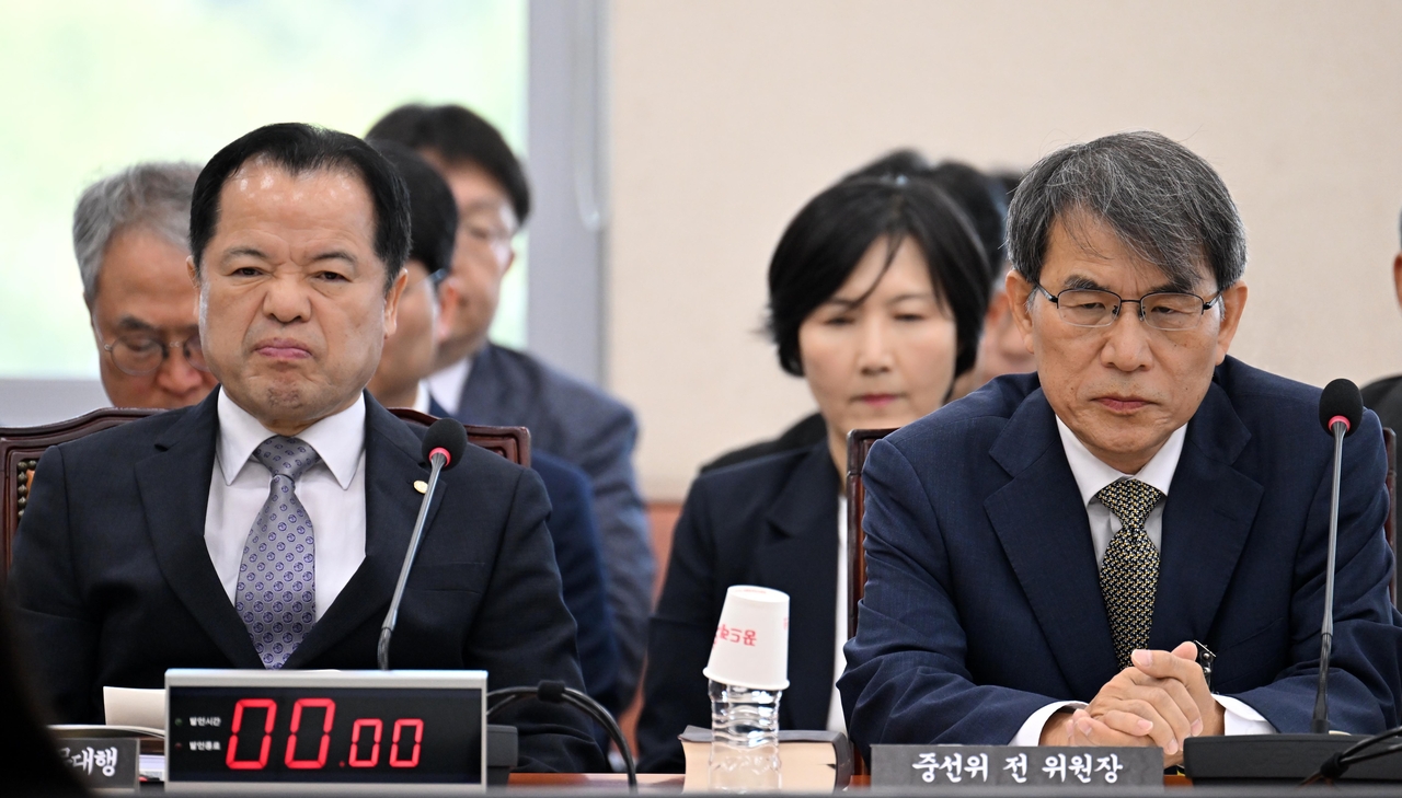 Wi Chul-hwan (left), commissioner and acting chair of the National Election Commission, and Rho Tae-ak, who was formerly chair of the NEC during the June 3 local elections, appear for a parliamentary session by the bipartisan special committee dedicated to investigating the election fiasco, at the National Assembly on Tuesday. (Lee Sang-sub/The Korea Herald)