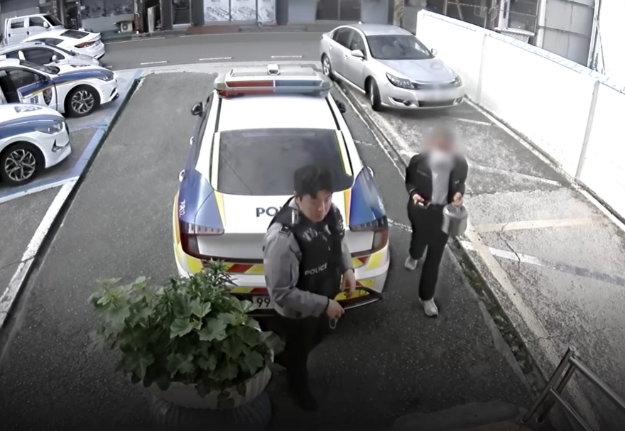 A security guard in his 70s carries a rice cooker containing gold he found at a recycling site into a local police station. (National Police Agency)