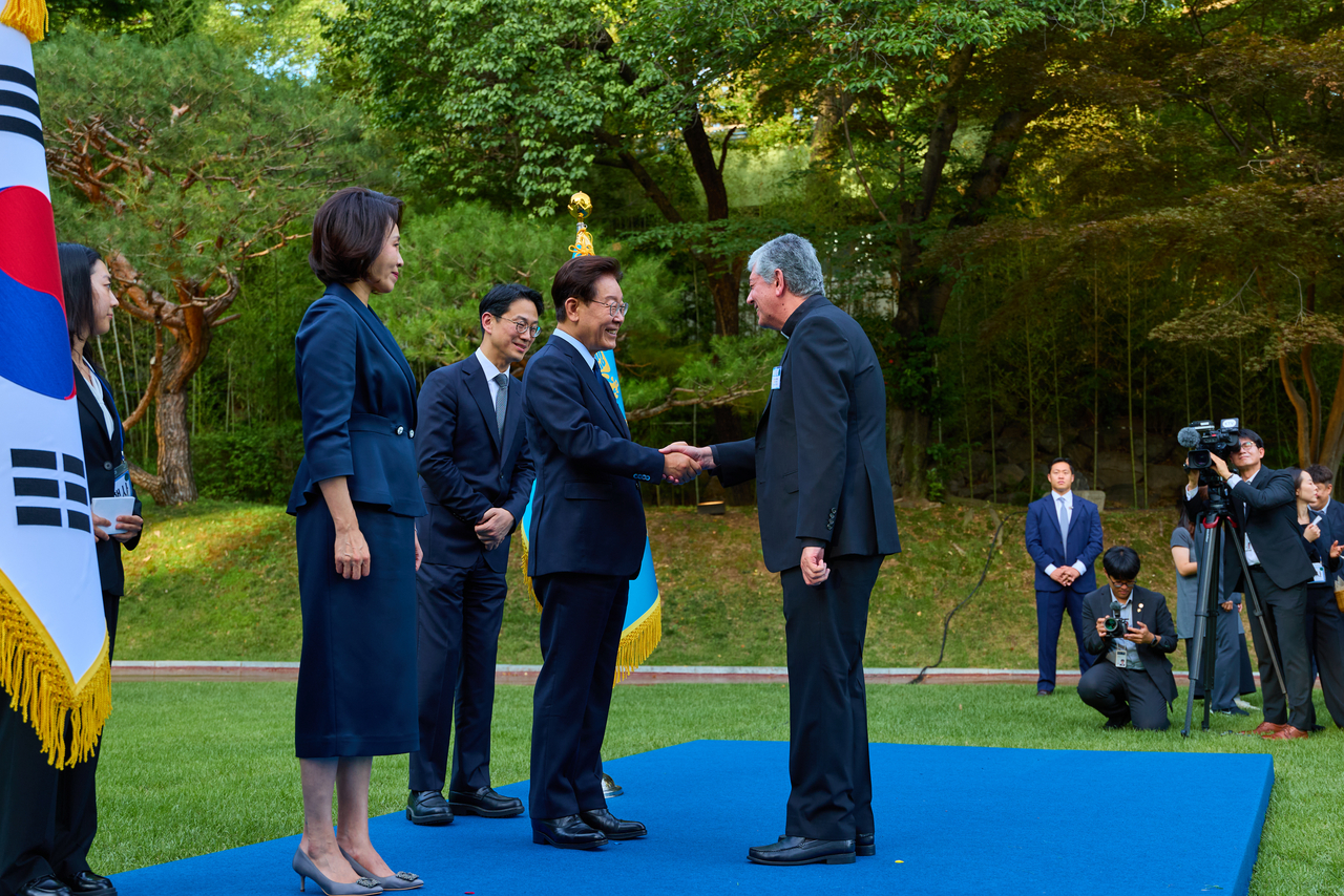 President Lee Jae Myung greets Archbishop Giovanni Gaspari, the Vatican's ambassador to South Korea, during a dinner reception for the diplomatic corps at Nokjiwon Garden in Cheong Wa Dae on Tuesday. (Cheong Wa Dae via Yonhap)