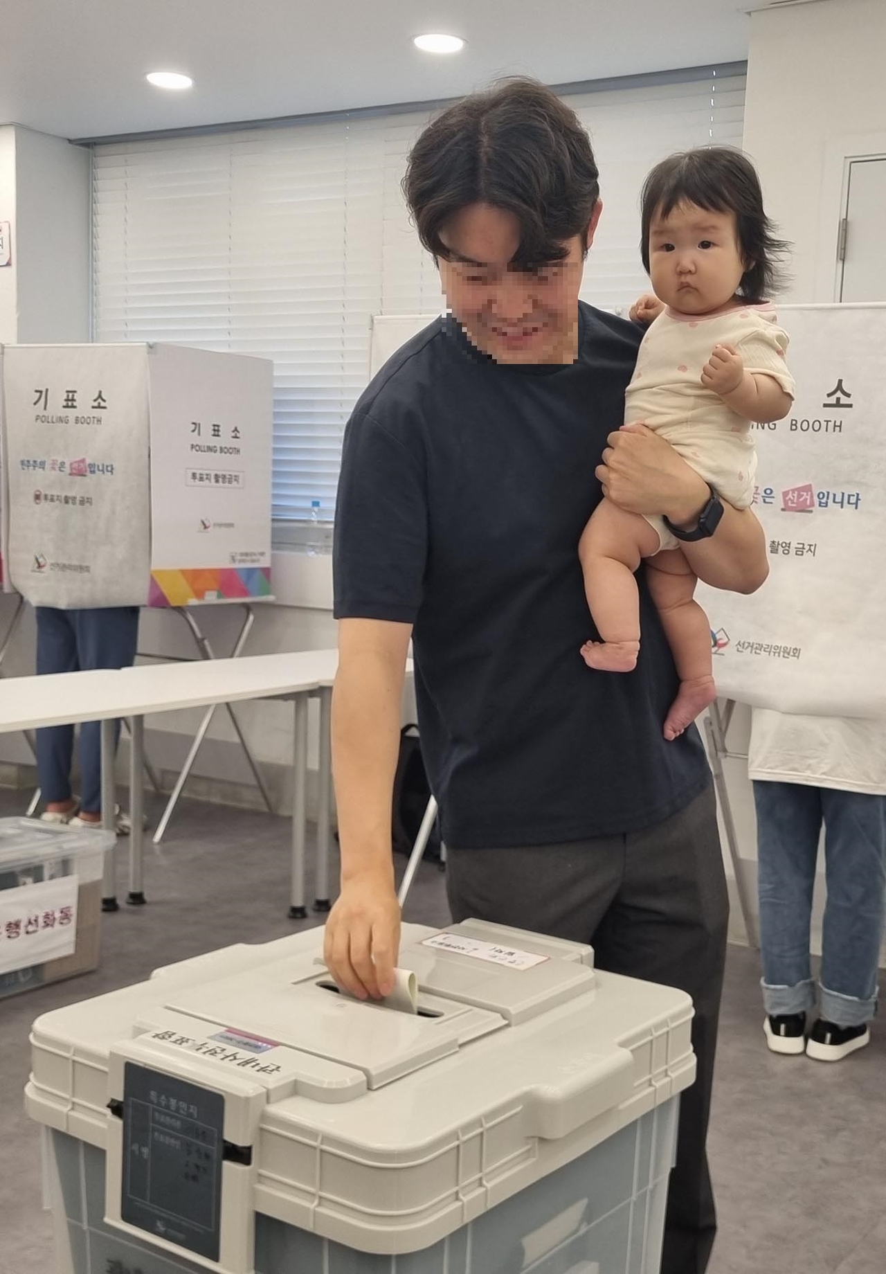 A father and his child at a polling station in Dajeon, during early voting in the local elections on May 29 (Yonhap)