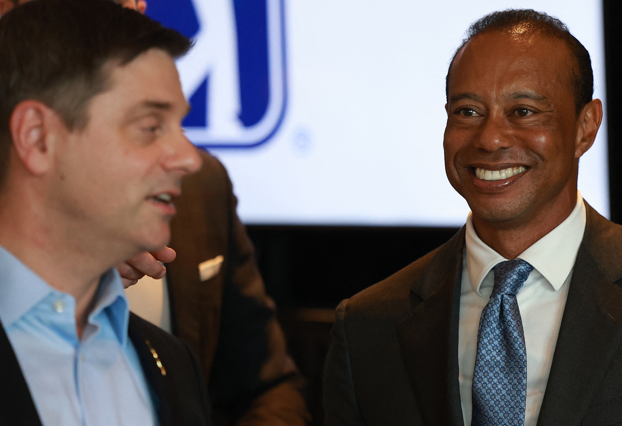 Brian Rolapp and Tiger Woods (right) at a press conference. [Getty Images]