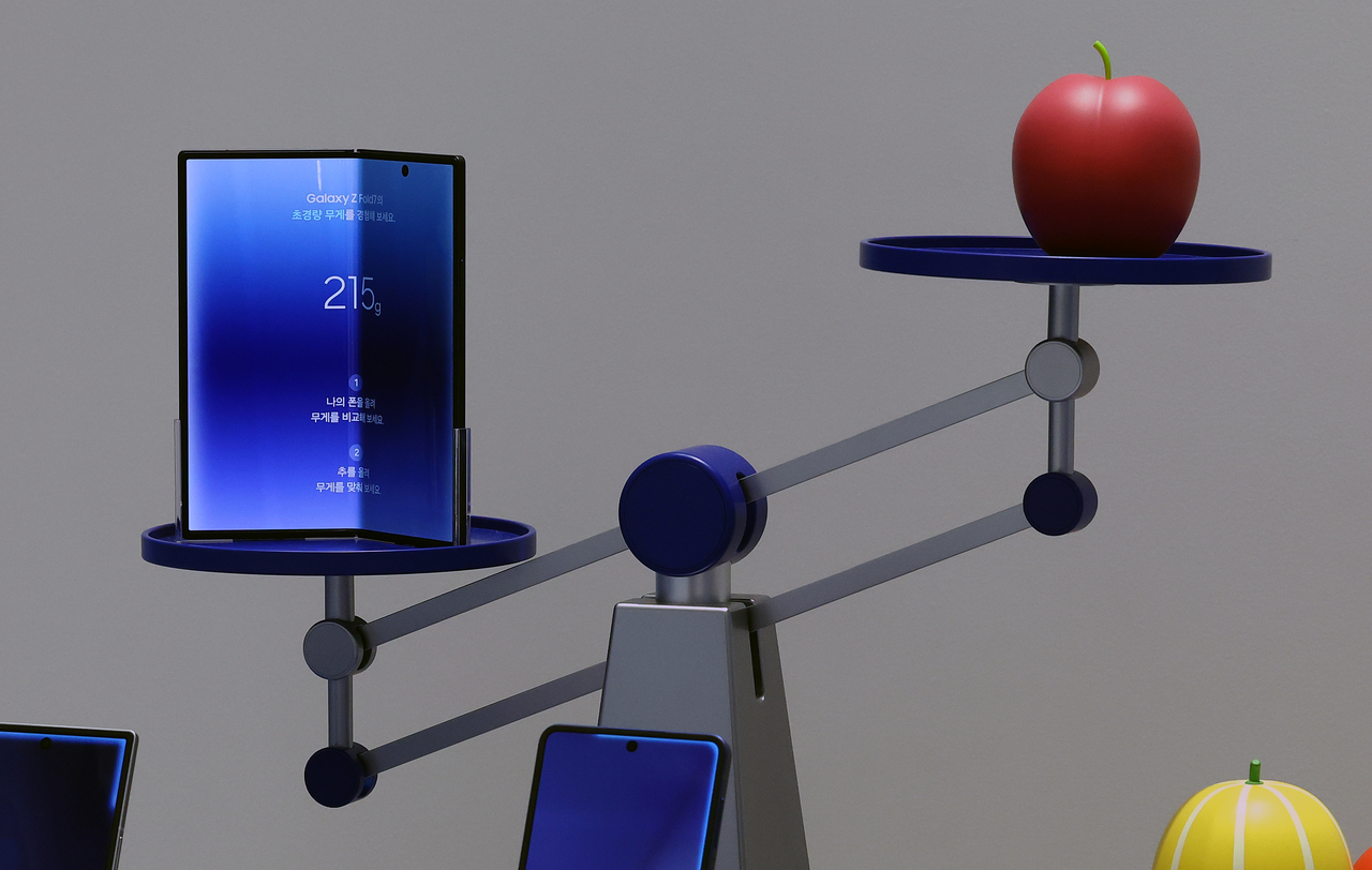 A weight-comparison display balances the 215-gram Galaxy Z Fold 7 against an apple at a Samsung store in Seoul during the phone's launch in July 2025. (Newsis)