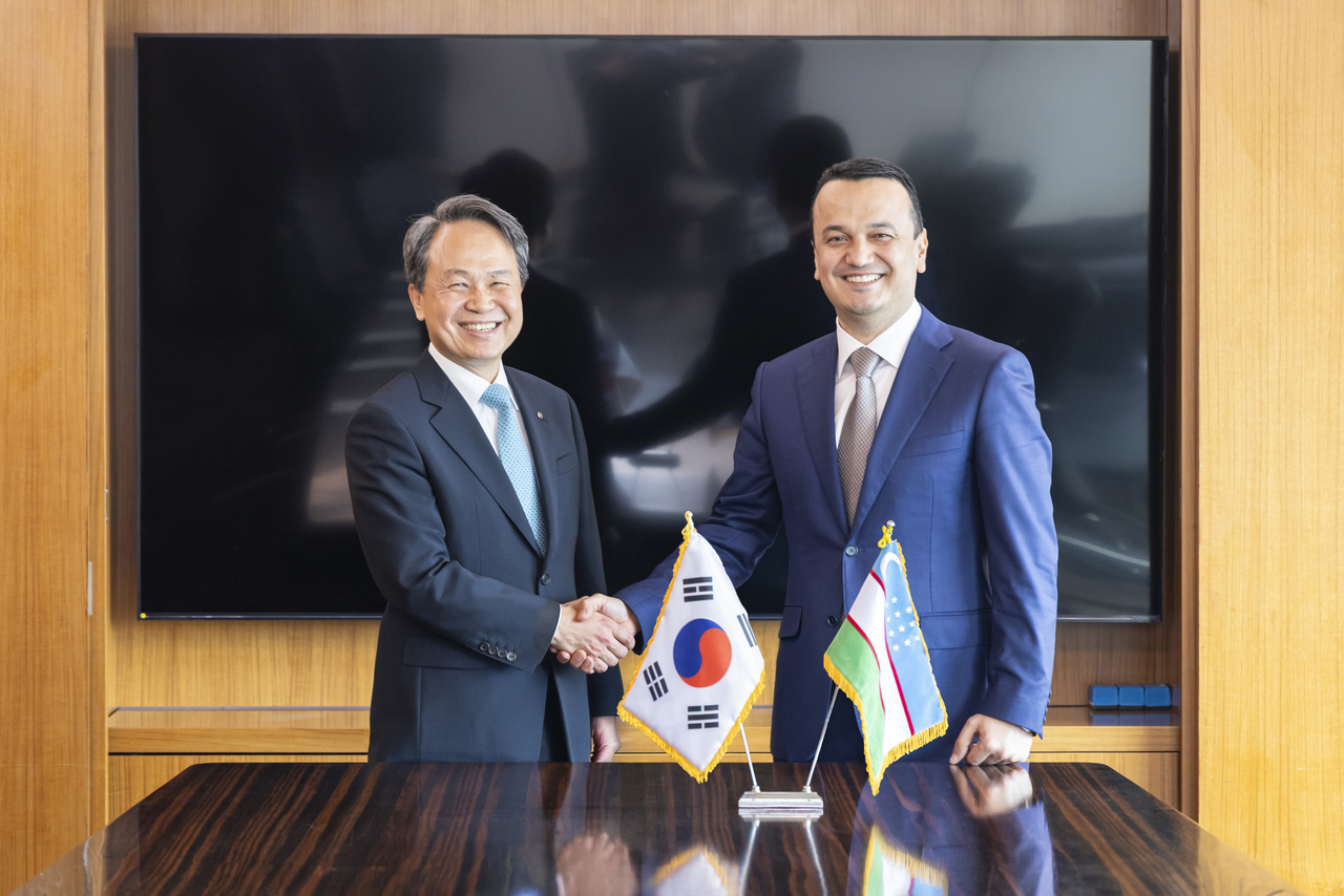 Shinhan Financial Group Chairman Jin Ok-dong (left) and Uzbekistan’s Minister of Investment, Industry and Trade Laziz Kudratov pose for a photo at a meeting at Lotte Hotel, central Seoul, Wednesday. (Shinhan Financial Group)