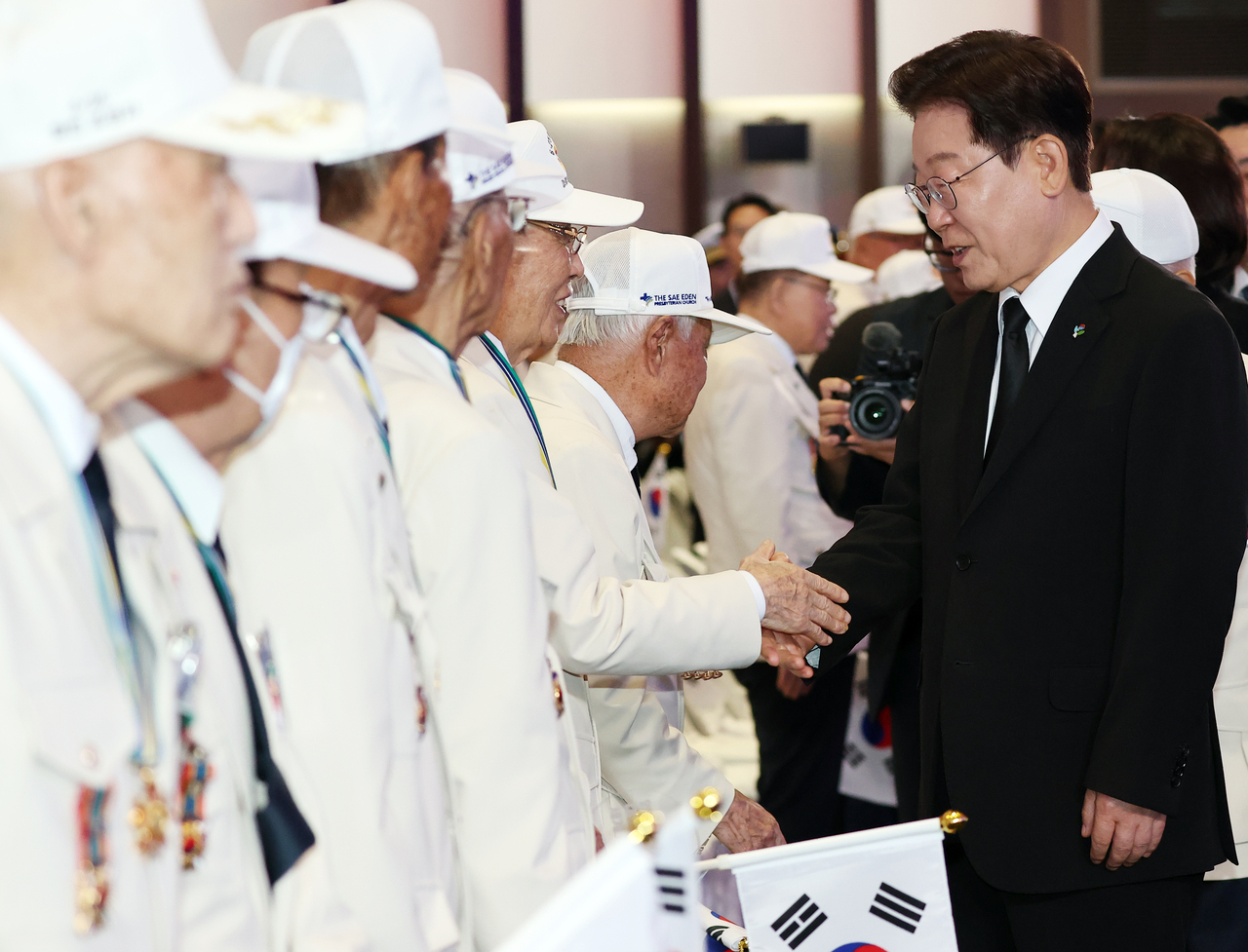 President Lee Jae Myung (R) shakes hands with a Korean War veteran during a ceremony marking the 76th anniversary of the outbreak of the 1950-53 Korean War at a convention center in Gyeonggi Province on Thursday. (Yonhap)