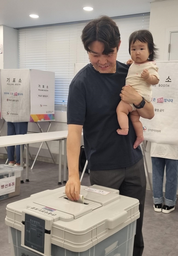 A father and his child visit a polling station in Daejeon for early voting on May 29 (Yonhap)