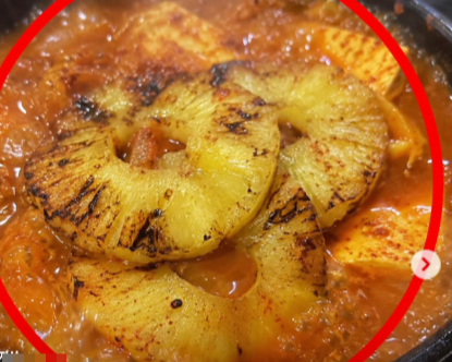 Slices of pineapple in a bubbling pot of kimchi jjigae