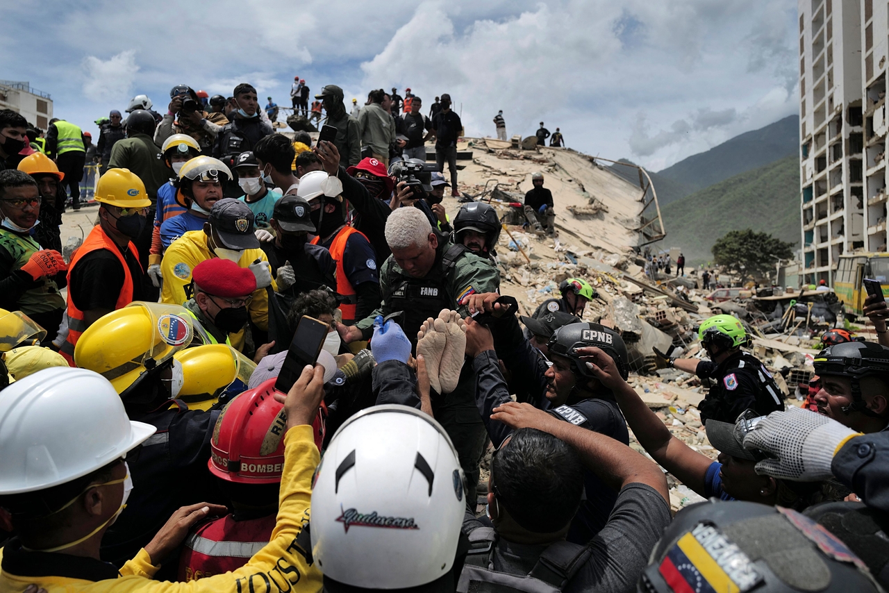 Rescuers carry a person after being pulled alive from the rubble of a collapsed building in Guaira, Venezuela, Sunday. (AFP-Yonhap)