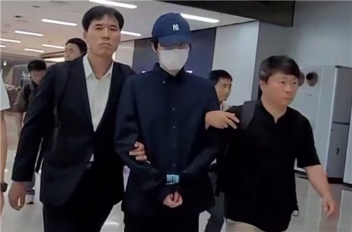 The alleged operator of the illegal webtoon site Newtoki is escorted through Gimpo Airport after being extradited from Japan on June 11. (Gyeongbuk Provincial Police Agency)