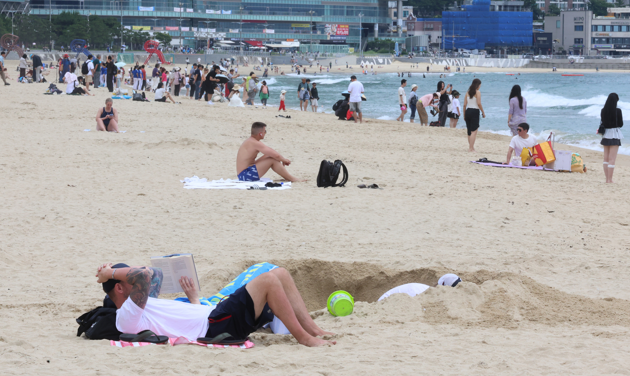 Visitors flock to Haeundae Beach in Busan on June 25, one day ahead of its official opening. (Yonhap)
