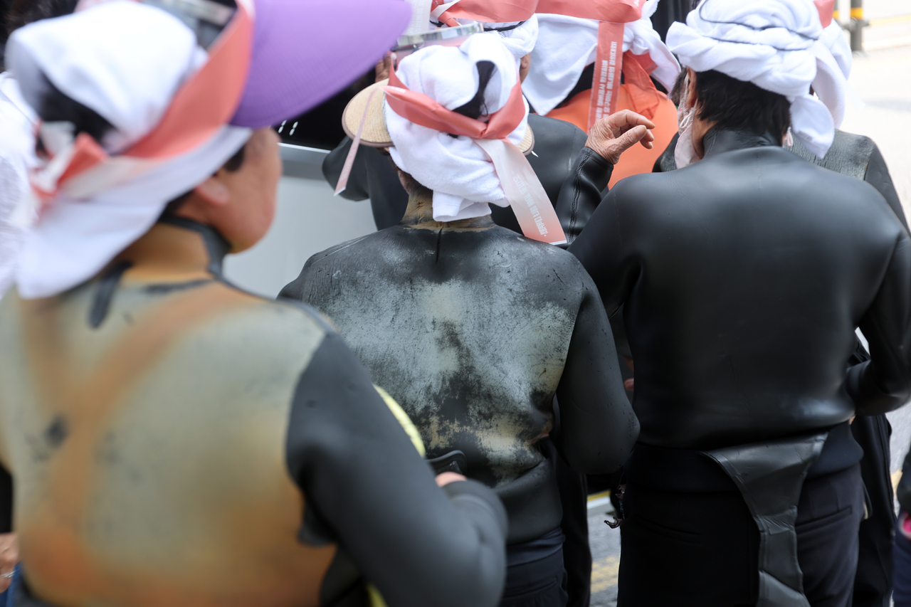 Wearing their traditional black diving suits, haenyeo, or traditional Korean female divers, head to a rally outside Ssangyong Engineering & Construction's headquarters in Seoul's Songpa District on Monday to demand compensation over the Homigot Harbor project. (Yonhap)