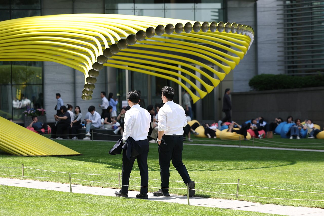 Office workers escape the heat in the shade near IFC Mall in Yeongdeungpo-gu, Seoul, on June 18. (Yonhap)
