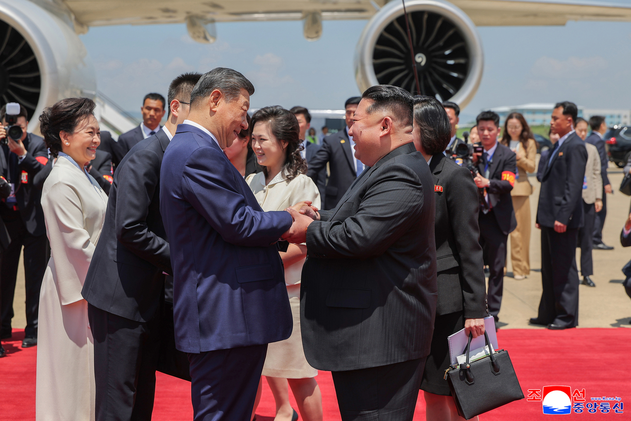 The North's leader Kim Jong-un (R) shakes hands with Chinese President Xi Jinping at Pyongyang Sunan International Airport on June 8. (KCNA via Yonhap)
