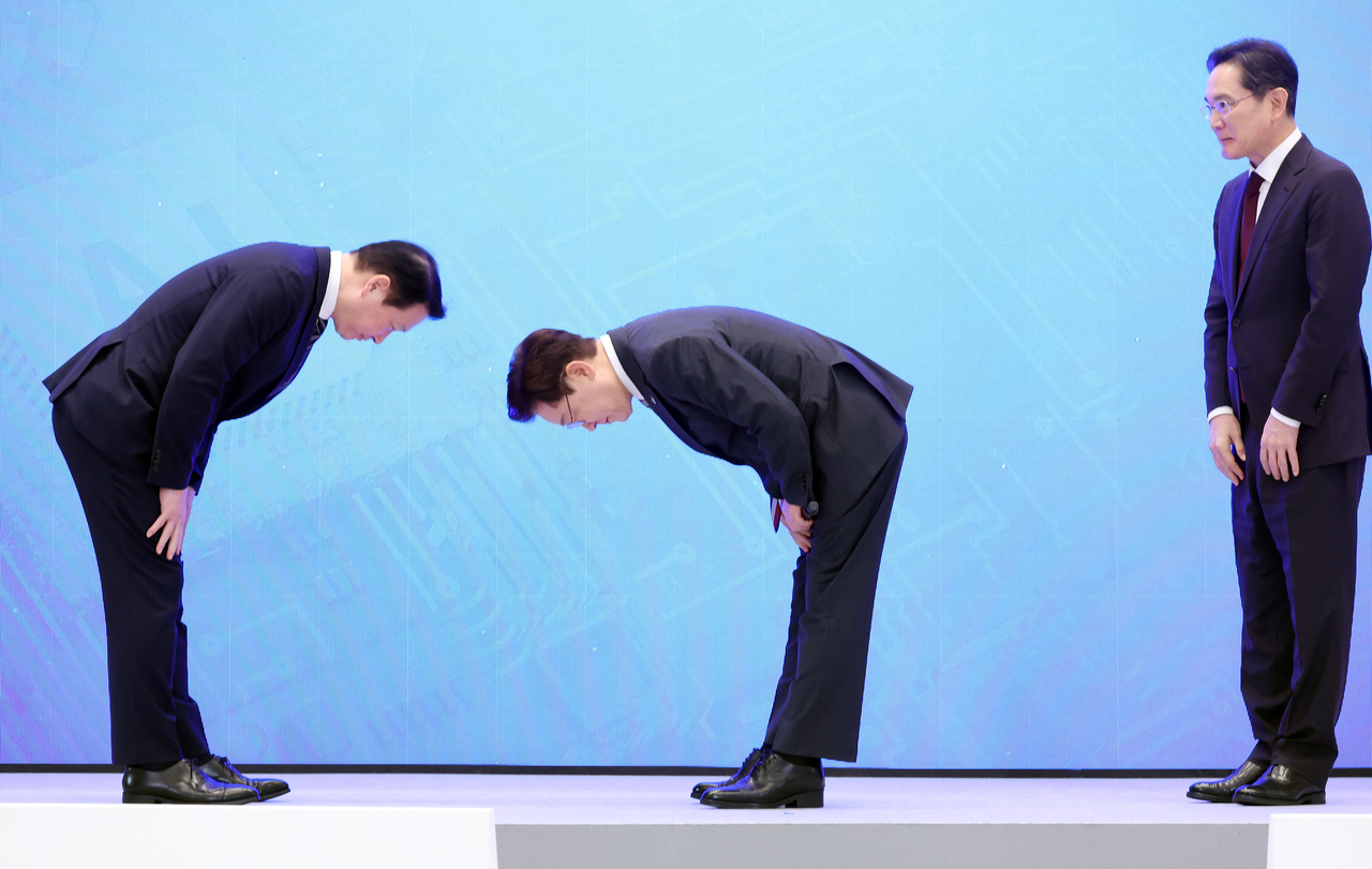 President Lee Jae Myung (center) bows deeply as he greets  SK Group Chairman Chey Tae-wo (left) following the announcement of corporate investment plans  at the presidential office in Cheong Wa Dae in Seoul on June 29. Chey also returns the bow, though Lee’s head is lowered further in the gesture. Samsung Group chief Lee Jae-yong is seen observing the exchange at right. (Yonhap)