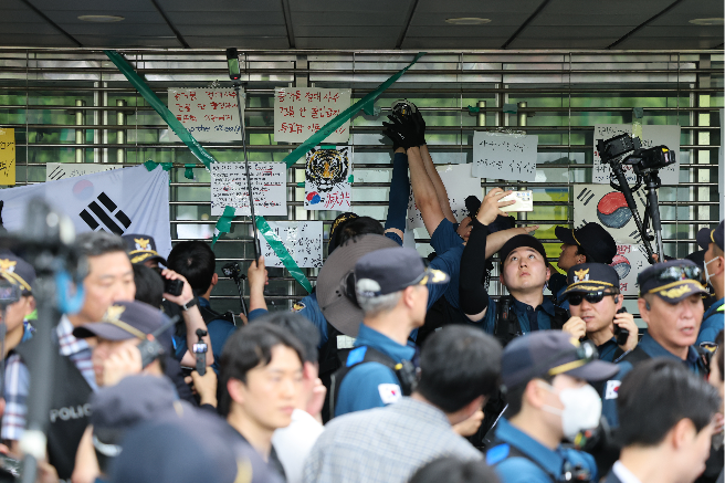 Police officers open the entrance of the Olympic Park Handball Gymnasium in southern Seoul, Thursday, to make way for the parliamentary special committee. (Yonhap)