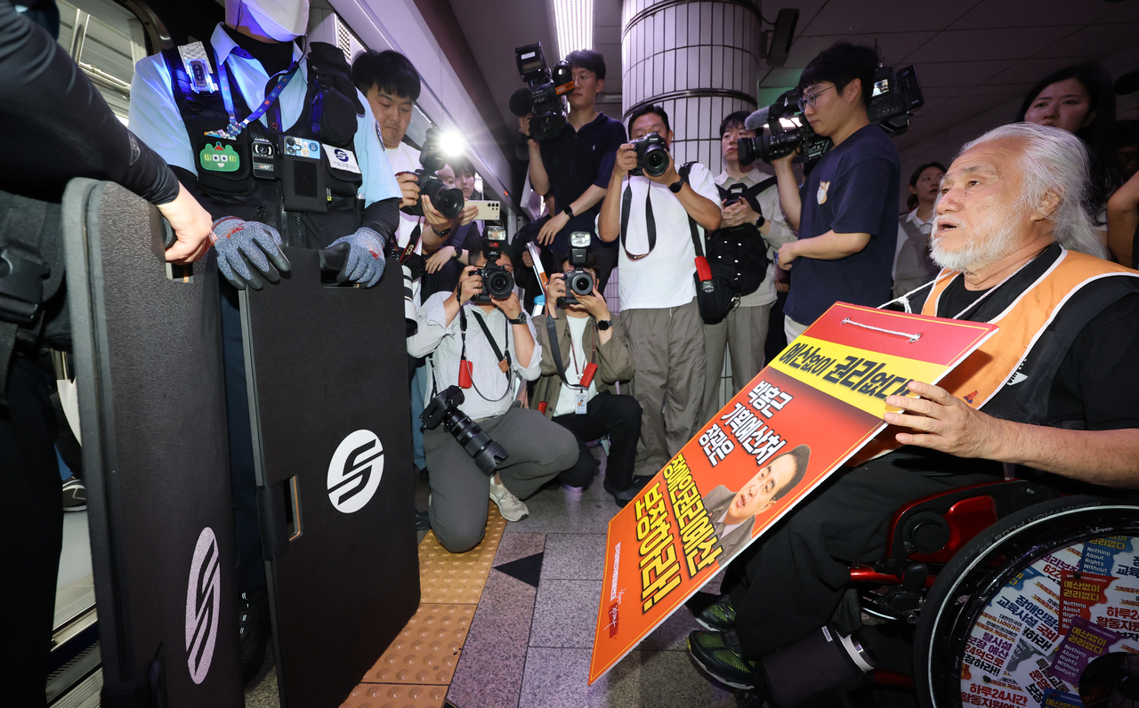 Park Kyoung-seok (right), chief of the Solidarity Against Disability Discrimination, holds a picket, calling for a government budget that covers the rights of the disabled, on the City Hall Station platform in Seoul on Thursday. (Yonhap)