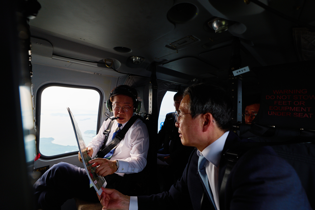 President Lee Jae Myung talks with presidential policy chief Kim Yong-beom during an aerial inspection of candidate sites for an industrial complex in South Korea’s southwestern region on June 30. (Cheong Wa Dae via Yonhap)
