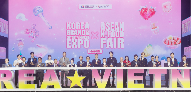 Korean and Vietnamese officials and brand ambassadors, including Winner and Fifty Fifty, pose for a photo during the opening ceremony of the Korea Brand and Entertainment Expo at the National Convention Center in Hanoi, Vietnam, Friday. (KOTRA)
