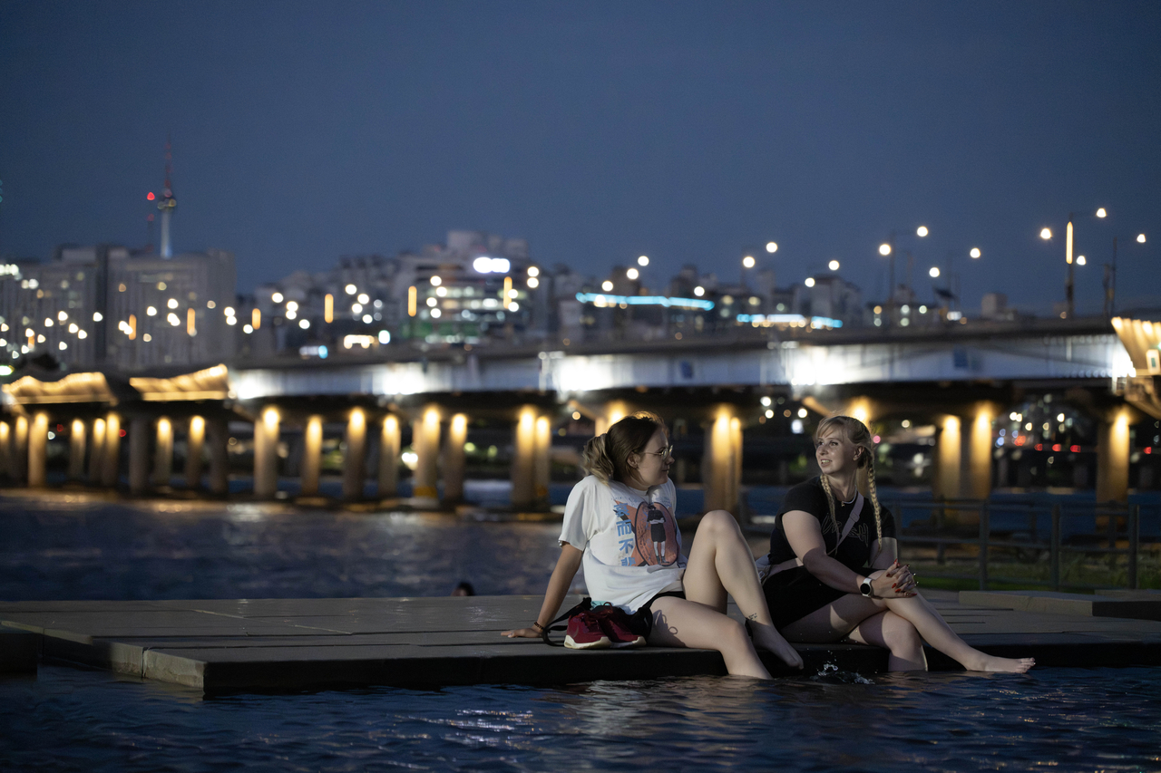 Visitors dip their feet in the water at Yeouido Hangang Park in Seoul, in this file photo taken on July 10, 2025. (Im Se-jun/The Korea Herald)