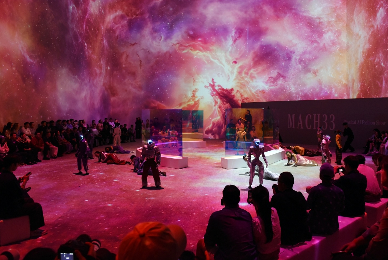 Visitors watch the MACH 33 Physical AI Fashion Show, where human performers and robots share the stage in an immersive multimedia production presented by Galaxy Corporation in May. (Galaxy Corporation)