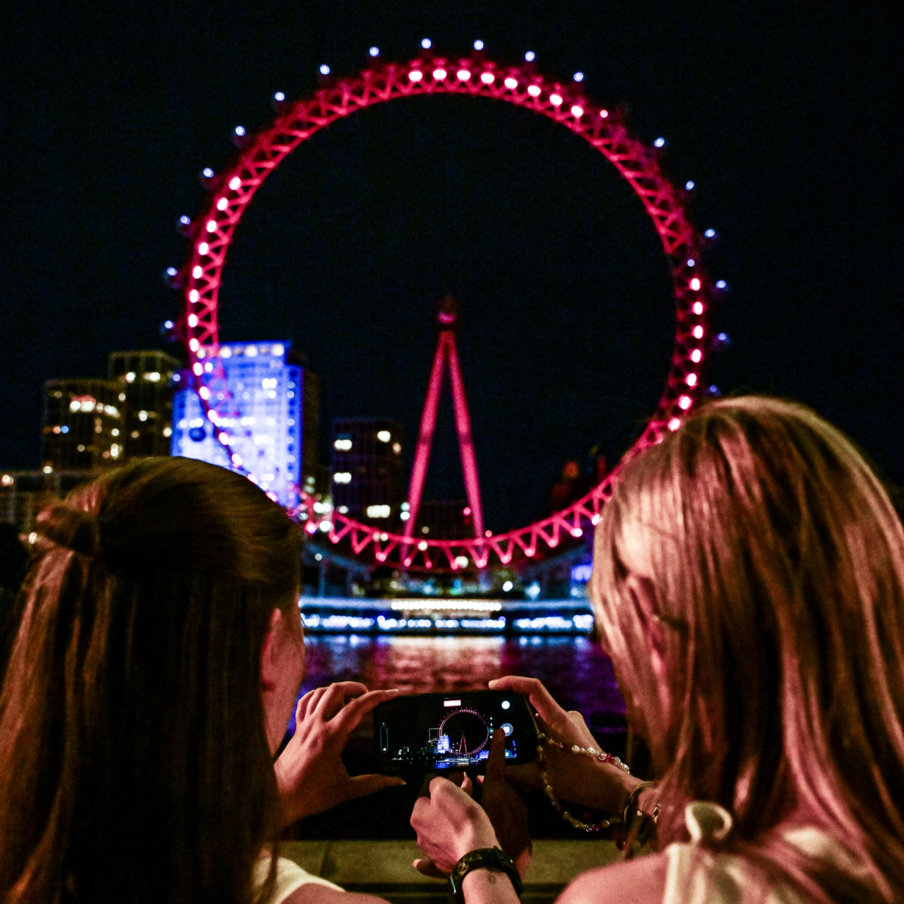 Fans take a picture of the London Eye illuminated in red as part of the “BTS The City Arirang" event in London. (Getty Images)