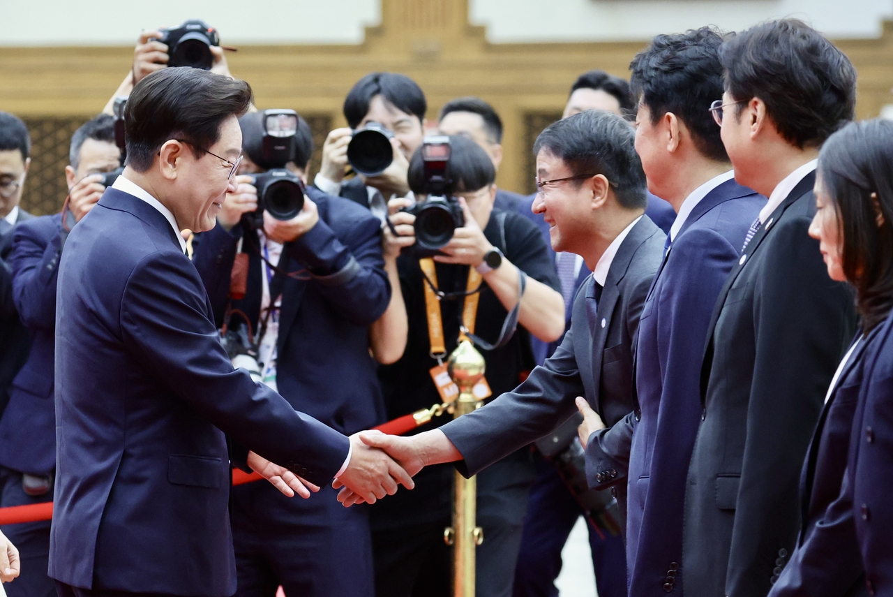 President Lee Jae Myung (left) shakes hands with Rep. Han Byung-do, the ruling Democratic Party's acting leader who came to see him off at Seoul Air Base in Seongnam on Tuesdday before his departure to attend the NATO Summit and pay a state visit to Mongolia. (Yonhap)