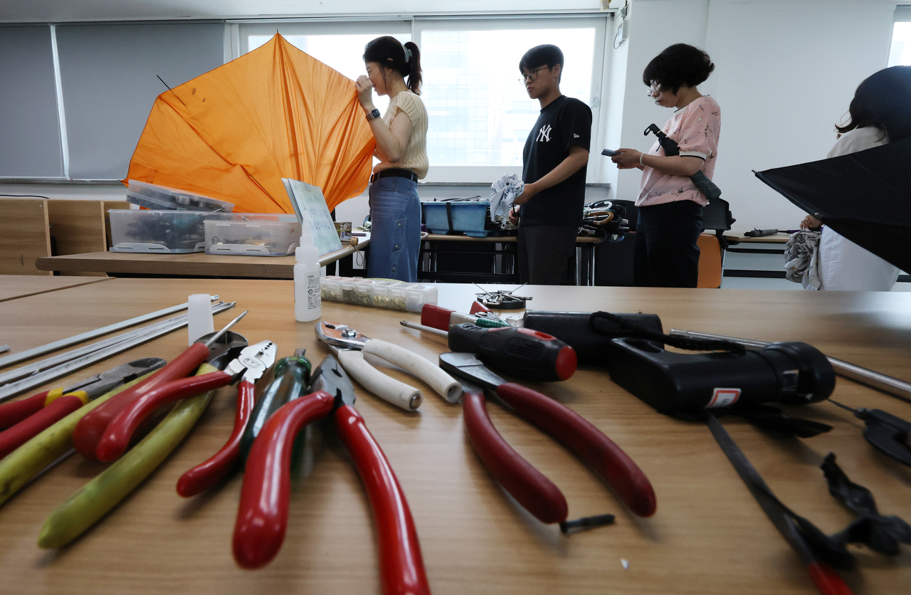 Residents wait in line for free umbrella and parasol repairs at the Samjeon-dong Community Service Center in Songpa-gu, Seoul, on Tuesay. (Yonhap)