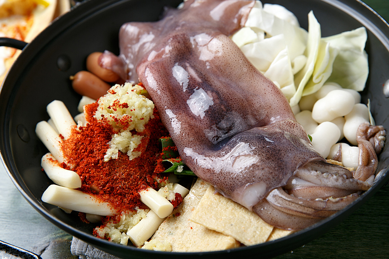 Uncooked stir-fried spicy seafood rice cake with sausage, fish cake, cabbage and squid on fry pan (123rf)
