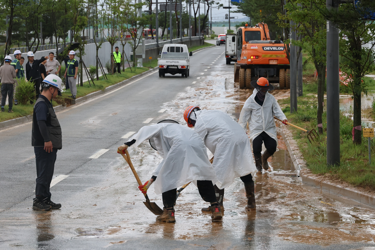 Workers remove soil and debris that spilled from a construction site near a BRT intersection in Hanbyeol-dong, Sejong, where vehicle traffic was restricted due to heavy rain on Wednesday. (Yonhap)