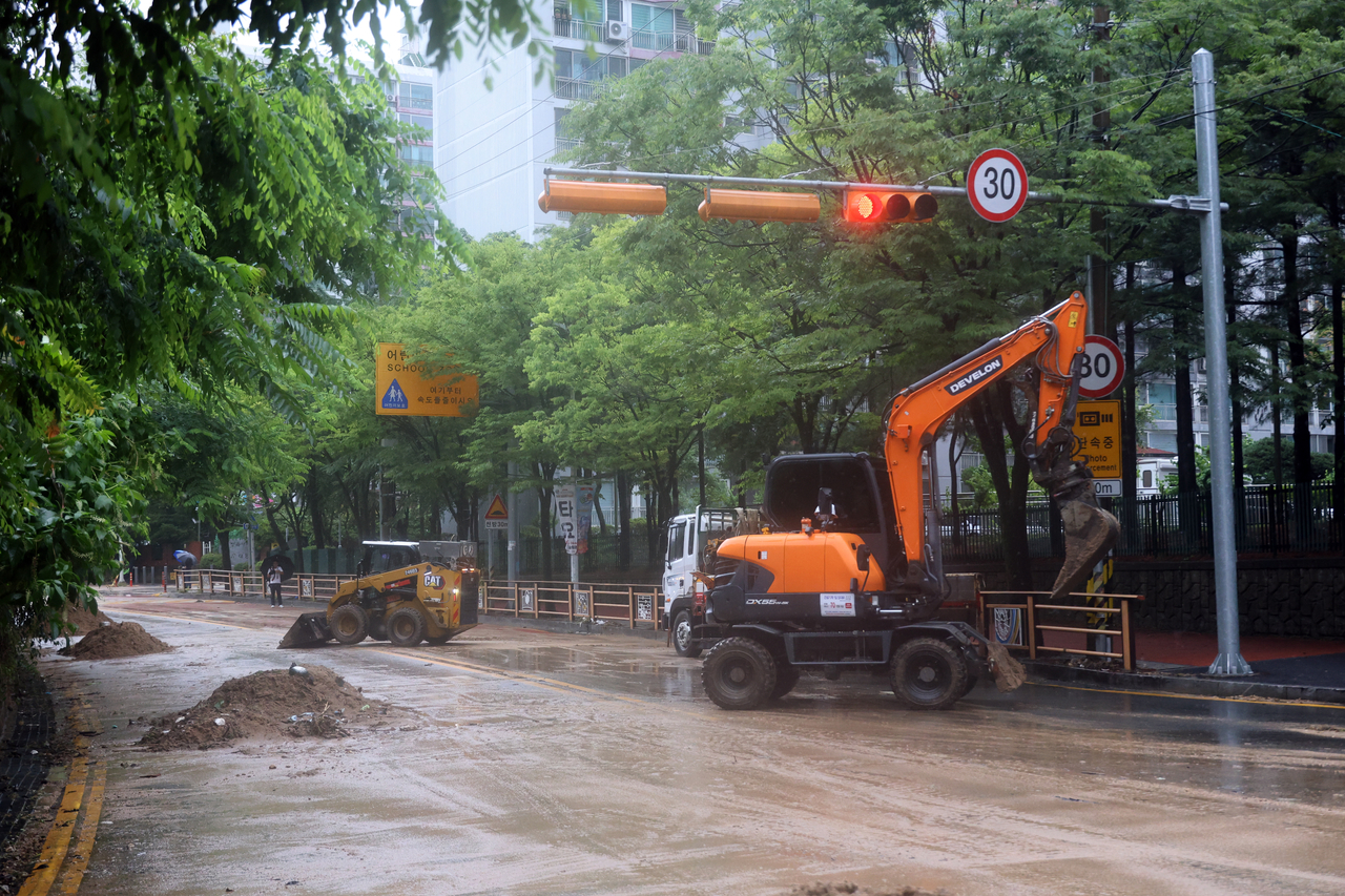 Workers clear mud from a road in front of an apartment complex in Songgang-dong, Yuseong-gu, Daejeon, on Thursday. (Yonhap)