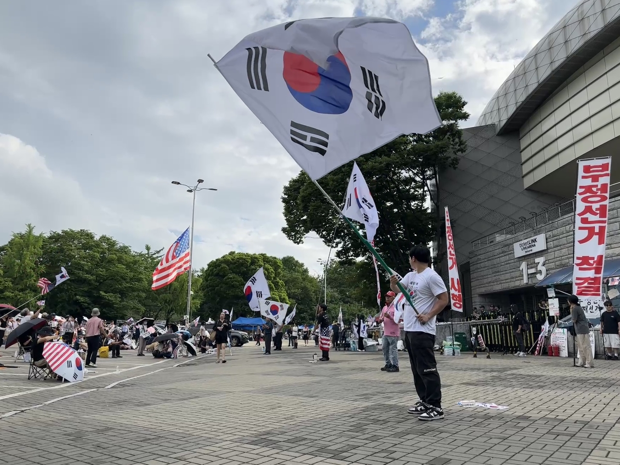 A demonstrator waves a South Korean flag at the Jamsil protest site on Wednesday afternoon. (Tammy Park/The Korea Herald)