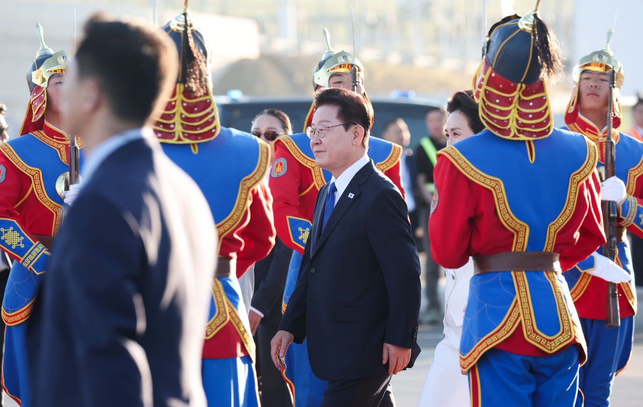 President Lee Jae Myung and First Lady Kim Hye-kyung walk toward their official vehicle after disembarking from Air Force One upon arriving at Chinggis Khaan International Airport in Ulaanbaatar on Thursday for a state visit to Mongolia. (Yonhap)