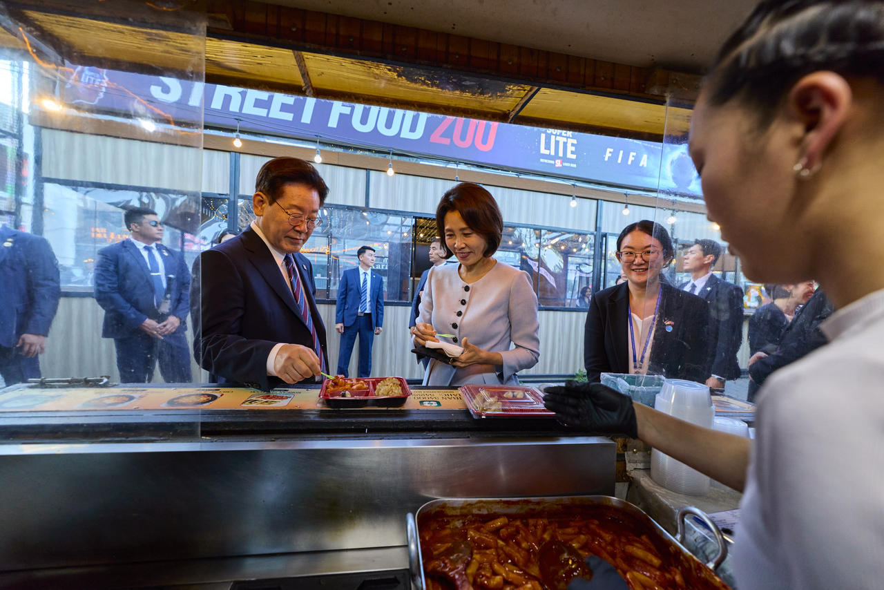 President Lee Jae Myung and first lady Kim Hea Kyung enjoy tteokbokki on Seoul Street in Ulaanbaatar on Thursday. (Yonhap)