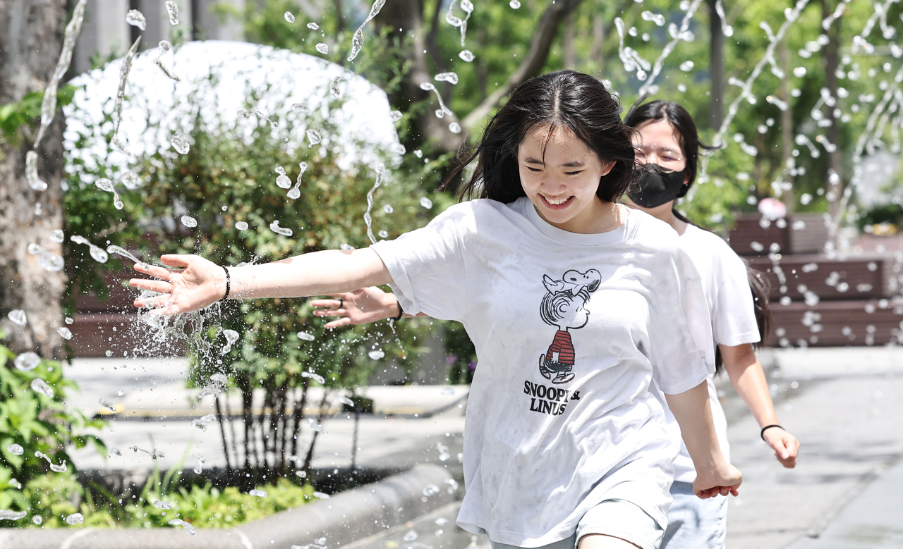 Students cool off by walking through a fountain at Gwanghwamun Square in Jongno-gu, Seoul, on July 7. (Yonhap)