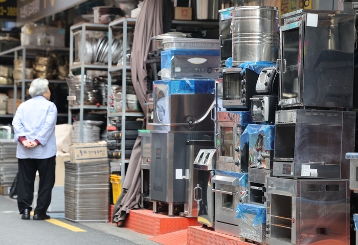 A study found that a 10% increase in the minimum wage raises the probability of business closure by 8.4 percentage points for self-employed owners with employees who have been operating for less than three years. The finding puts a number to long-held concerns that minimum wage hikes push already-marginal small business owners toward shutting down. Pictured are used kitchen appliances piled up for resale in Seoul's Hwanghak-dong kitchen supply district following business closures. [Yonhap]