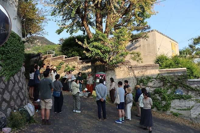 Residents of Buam-dong in Seoul's Jongno-gu inspect a ginkgo tree next to the Whanki Museum. The museum faces allegations that it injected poison into the tree in an attempt to kill it. [Provided by Seoul Environment Federation]